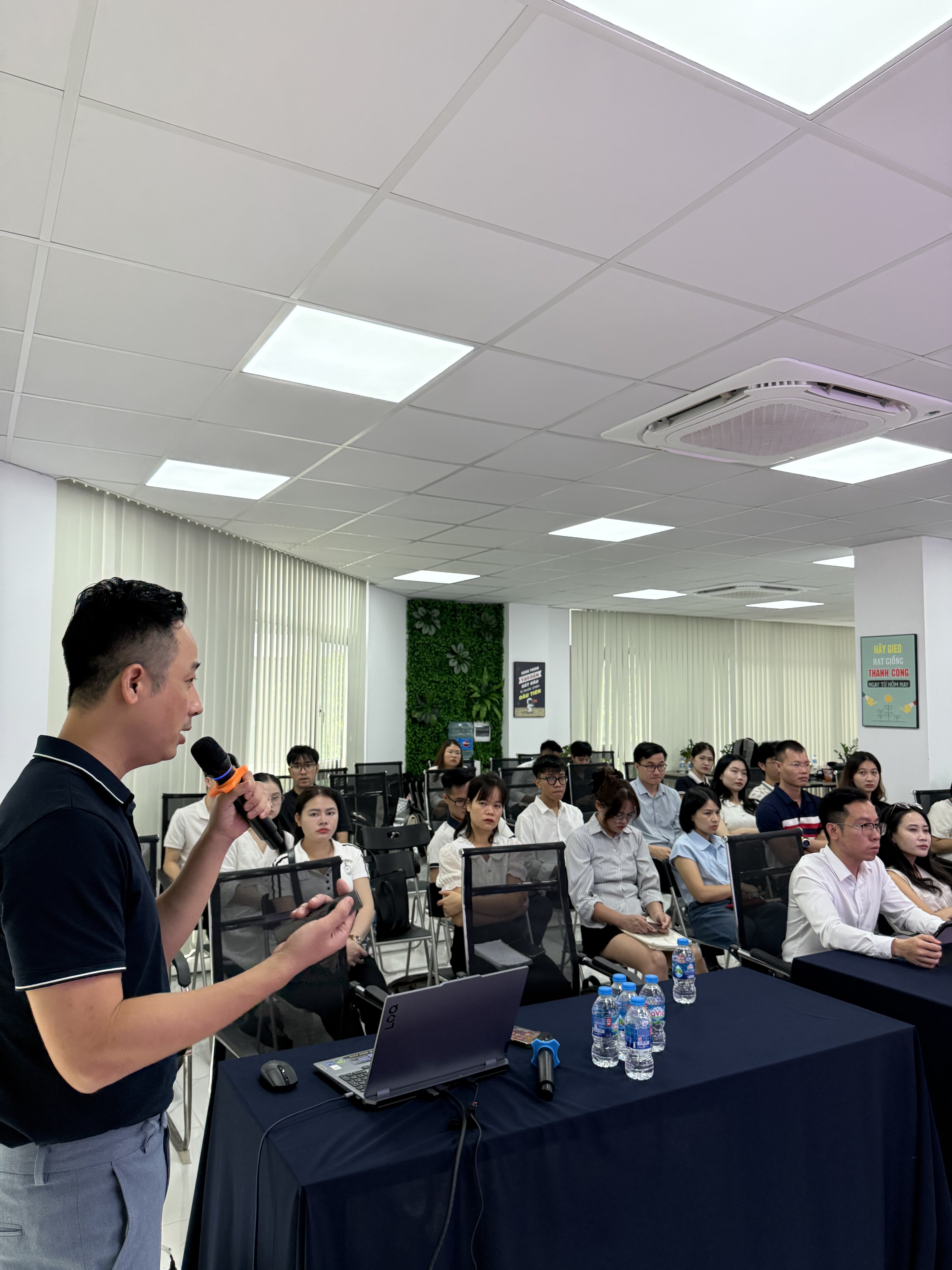 Đăng Dương cầm micro đứng trước lớp học viên ngồi kín bàn máy tính trong văn phòng sàn giao dịch