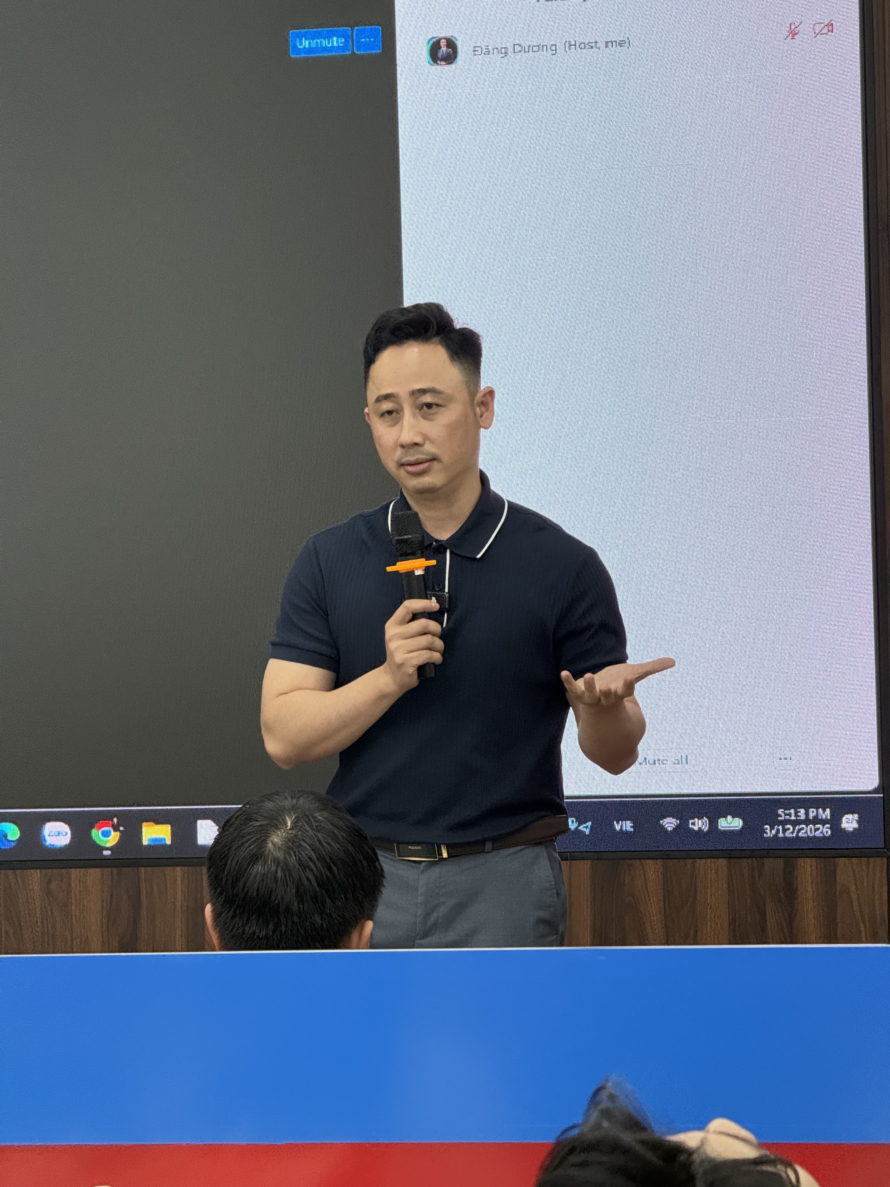 Đăng Dương cầm micro đứng trước màn hình chiếu giao diện một nền tảng mạng xã hội