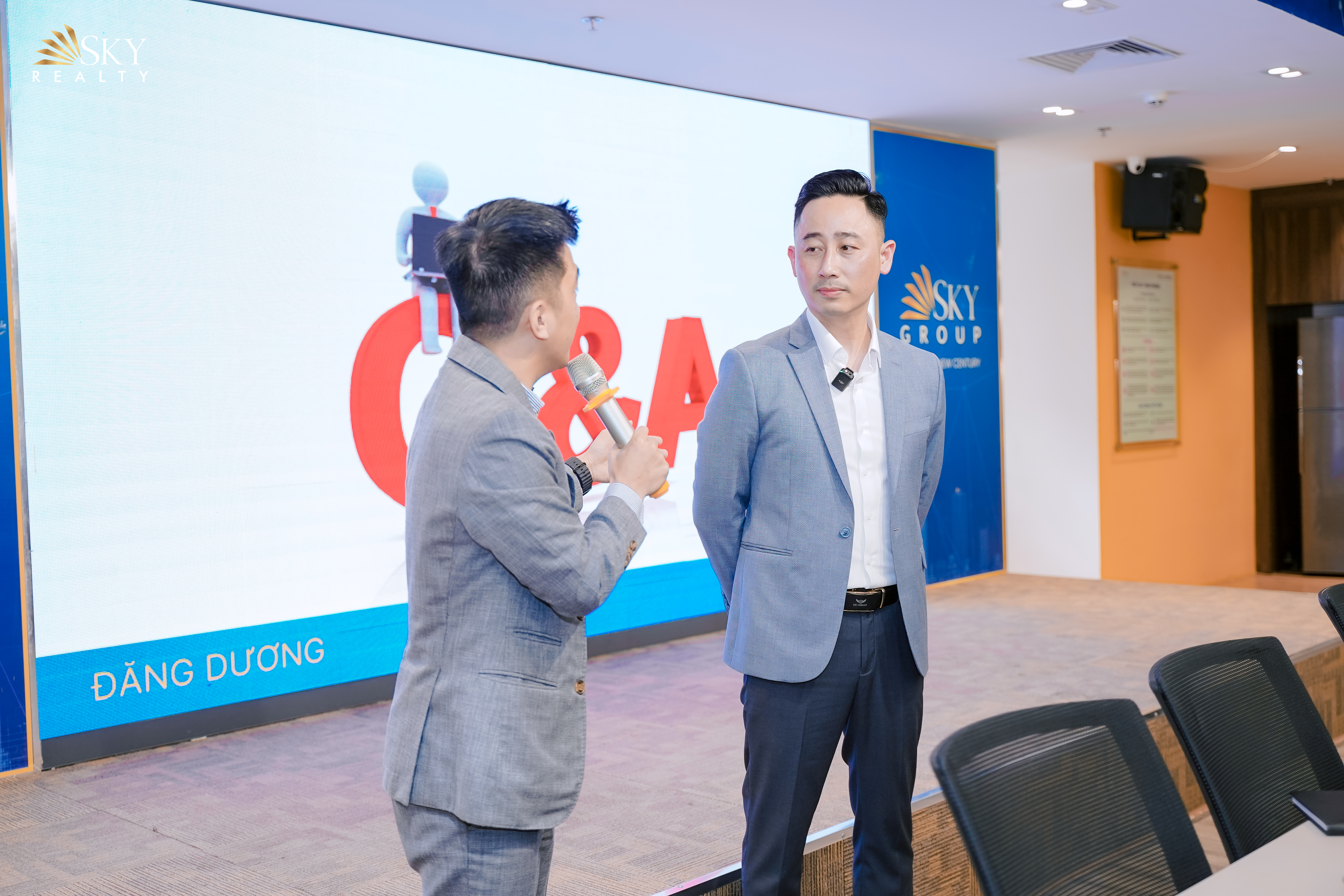 Đăng Dương mặc vest xám trao đổi trên sân khấu hỏi đáp cùng người dẫn chương trình