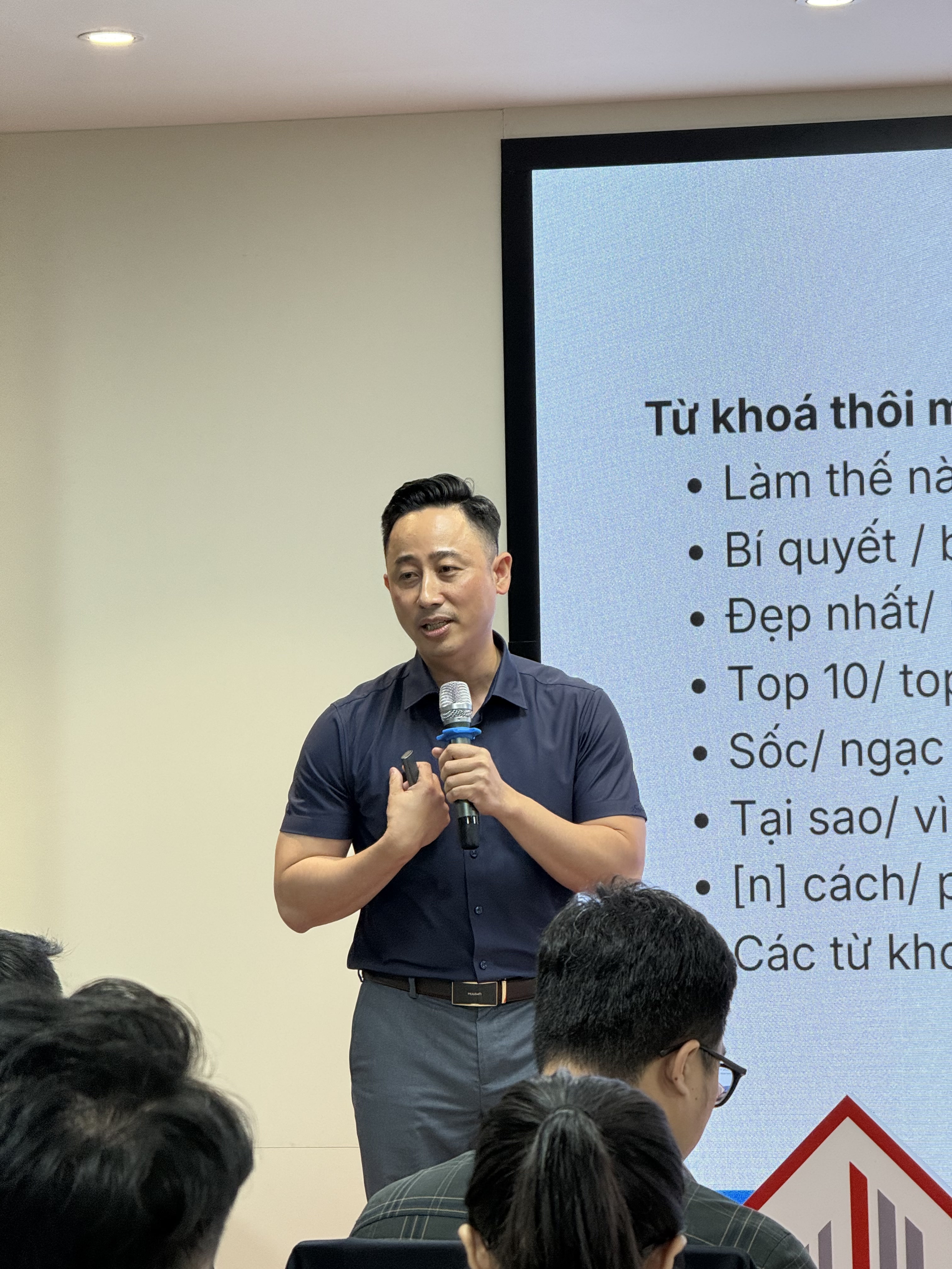 Đăng Dương cầm micro nói trước lớp môi giới, màn hình phía sau chiếu danh sách từ khoá thu hút người xem
