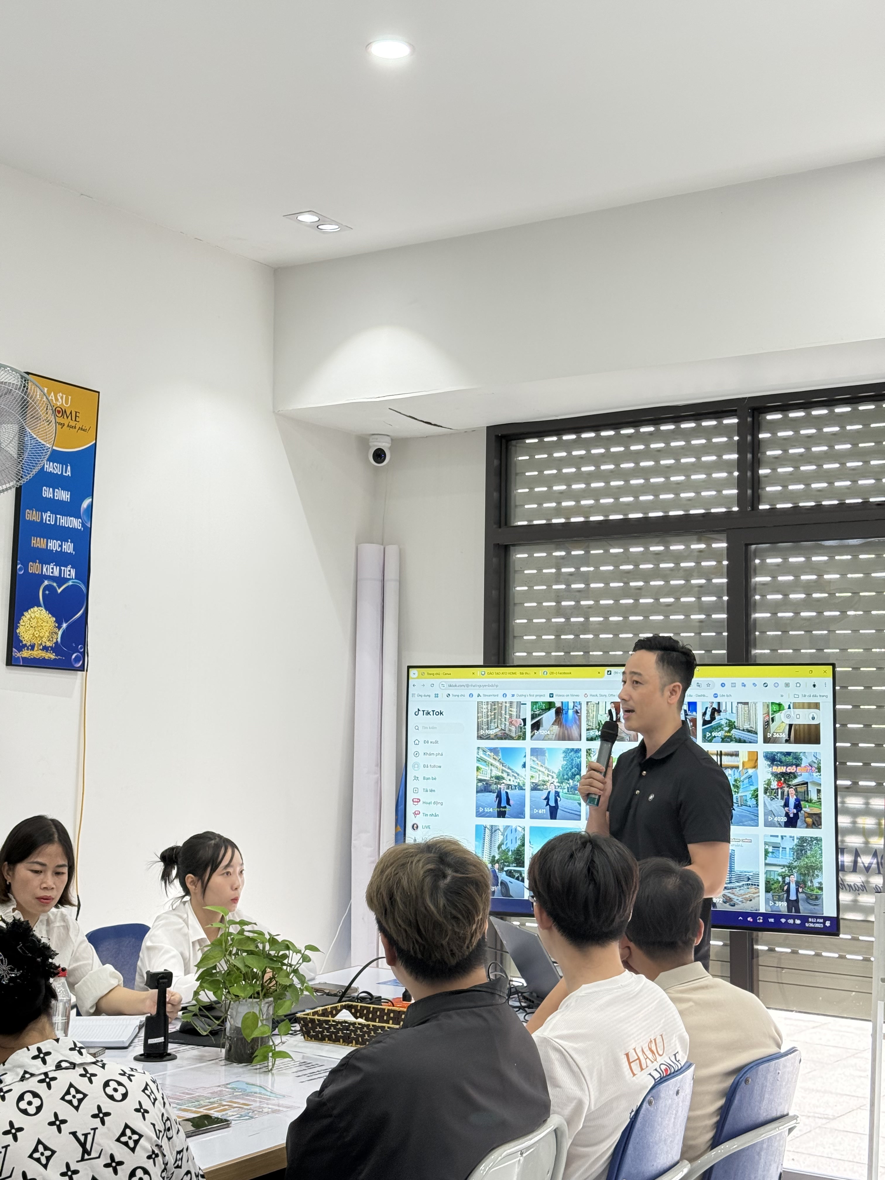 Đăng Dương đứng cạnh màn hình lớn chiếu lưới ảnh sản phẩm bất động sản, học viên ngồi nghe phía trước