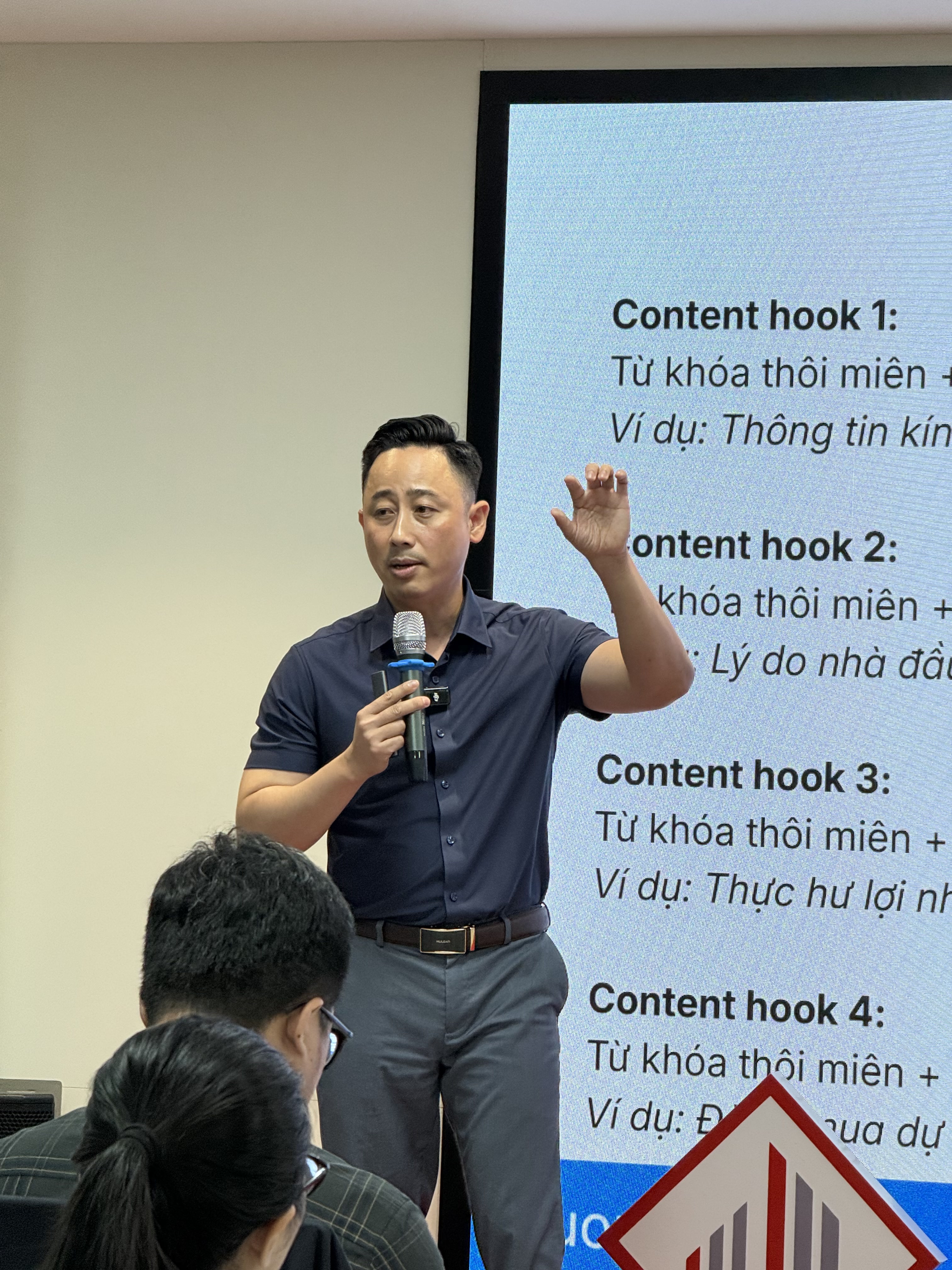 Đăng Dương giơ tay chỉ lên màn hình đang chiếu các mẫu câu mở đầu video bất động sản