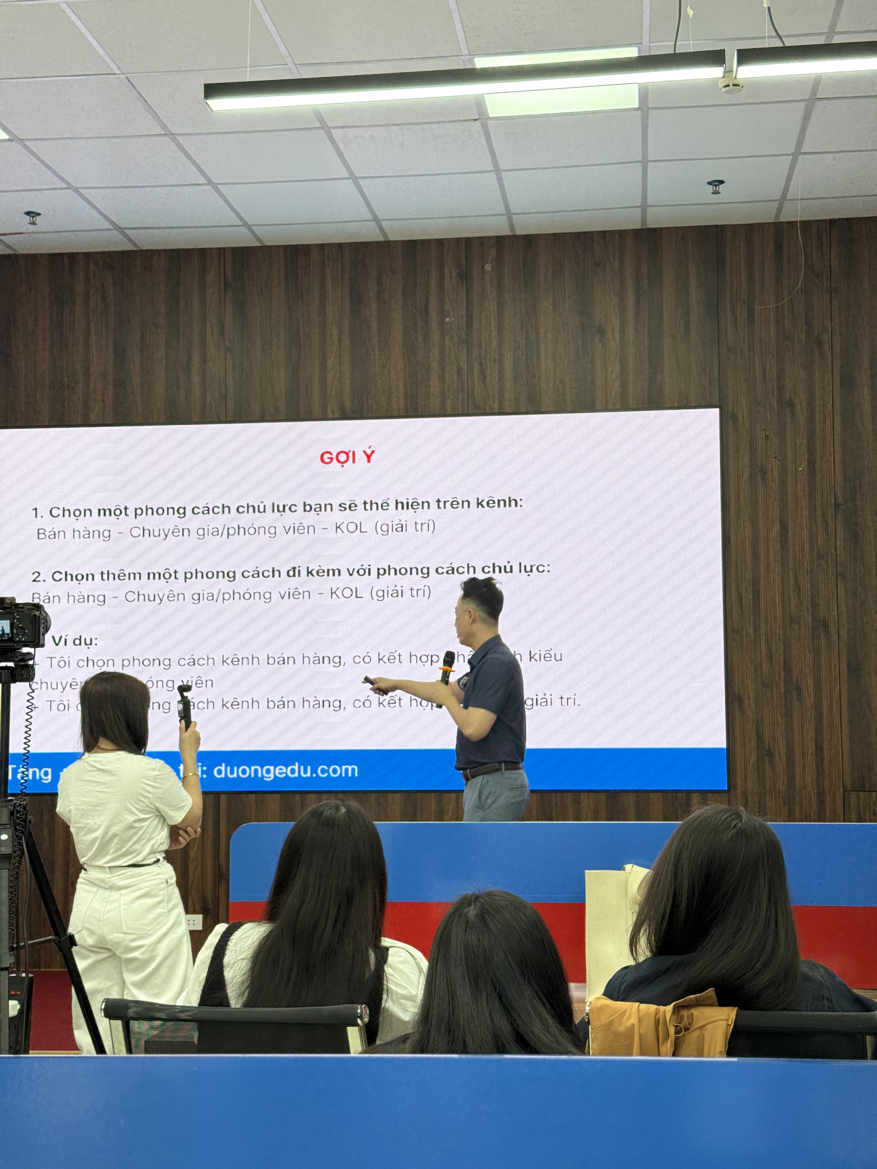Đăng Dương giơ tay chỉ lên màn hình chiếu trang cá nhân của một học viên