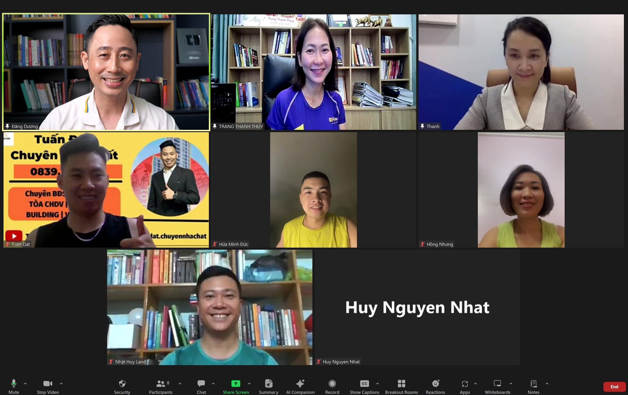 Màn hình cuộc họp Zoom với tám người tham gia, mỗi người ngồi trước giá sách hoặc bàn làm việc riêng