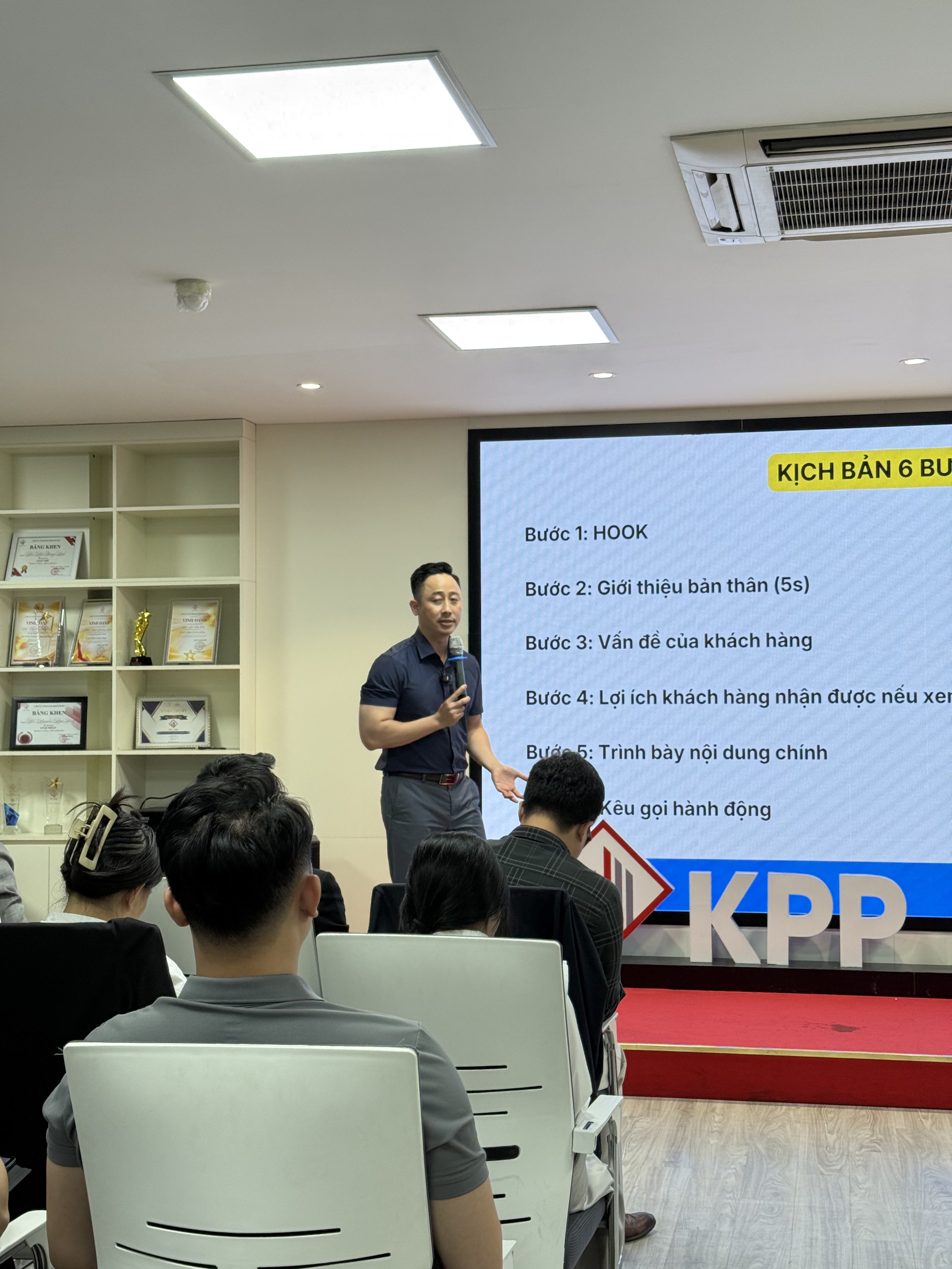 Đăng Dương đứng trước màn hình chiếu kịch bản sáu bước cho một video bất động sản